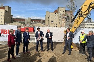 Foto von mehreren Personen im Anzug die eine Röhre vergraben.  