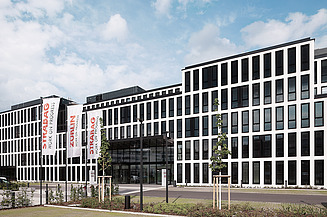 Office Cologne The photo shows the Office at the Cologne site with STRABAG and ZÜBLIN flags in front of the building.