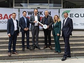 Foto von sechs stehenden Personen bei der symbolischen Baufeldübergabeabe