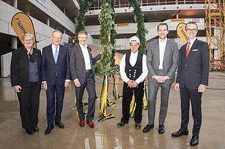 Foto von freundlich schauenden Personen vor dem Richtkranz.