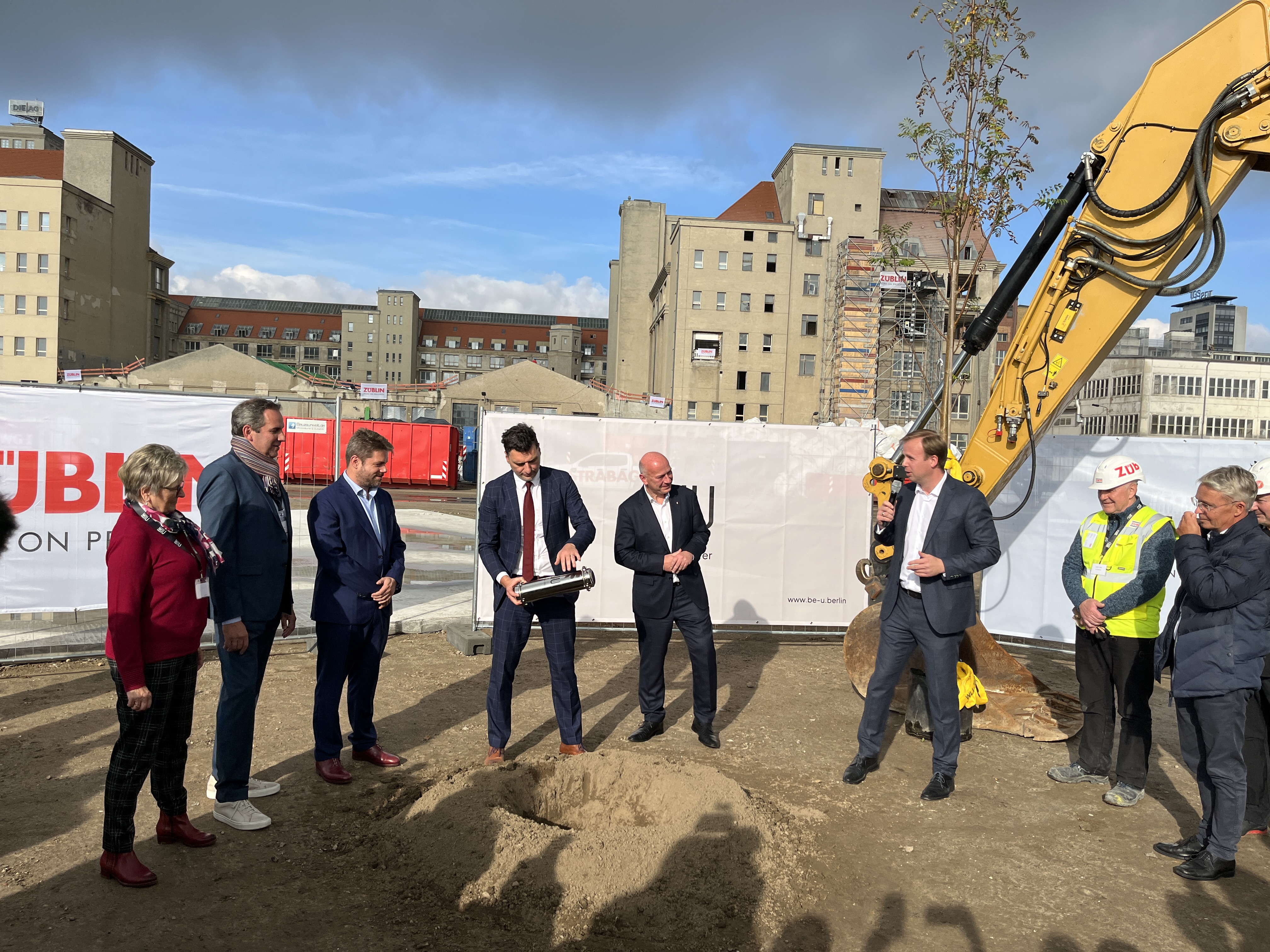 Foto von mehreren Personen im Anzug die eine Röhre vergraben.  