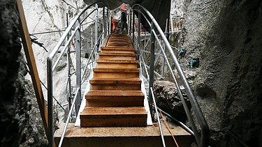 Foto von einer Brücke die durch eine Schlucht führt, an der gebaut wird.   