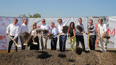 Photo of several people with shovels in their hands at a symbolic groundbreaking ceremony