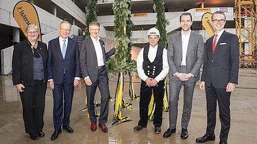 Foto von freundlich schauenden Personen vor dem Richtkranz.