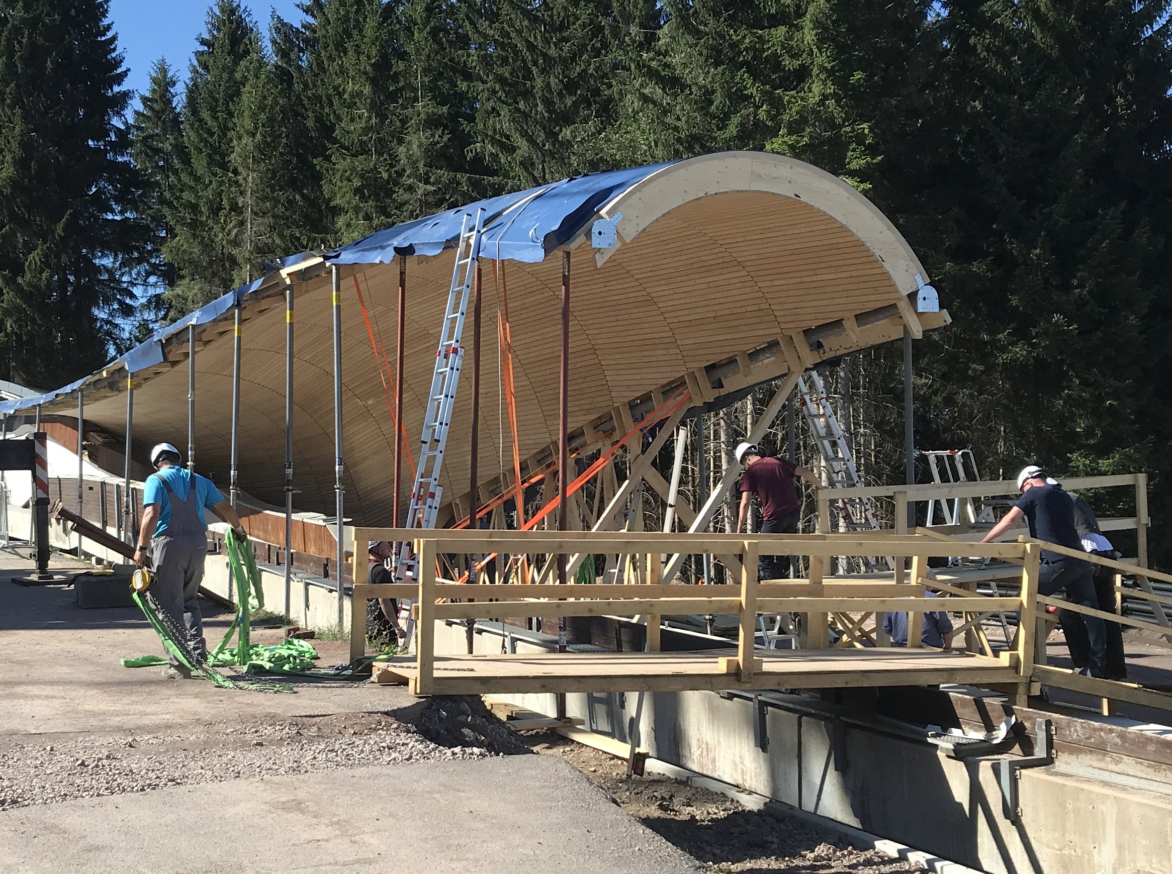 Foto von einer Baustelle im Wald, wo eine Überdachung aus Holz gebaut wird.      