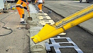 Foto von zwei Straßenbauarbeitern mit einer gelben Maschine