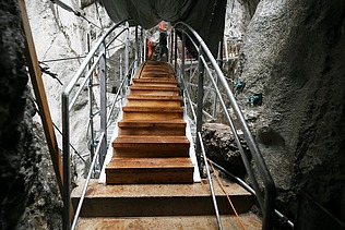 Foto von einer Brücke die durch eine Schlucht führt, an der gebaut wird.   