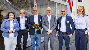 Elegant gekleidete Menschen stehen vor einem Zelt