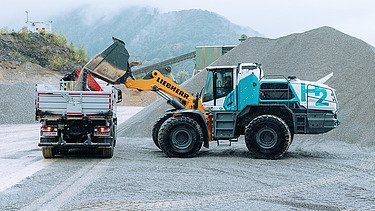 Photo of a wheel excavator pouring soil into a truck