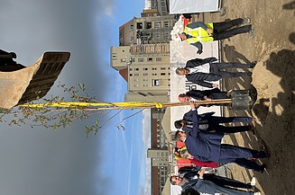 Foto von mehreren Personen im Anzug die einen Baum einpflanzen.   