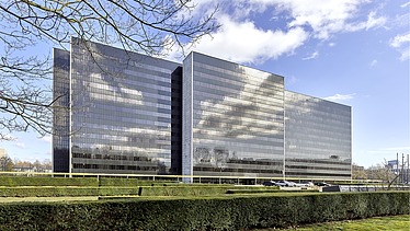 The picture shows an office building with a glass façade
