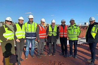 Foto von mehreren Personen die in Warnwesten auf einer Baustelle stehen.  