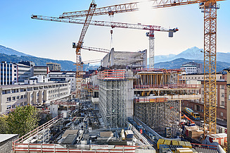 Foto von einer Baustelle eines Hochhaus umzingelt von mehreren Kränen