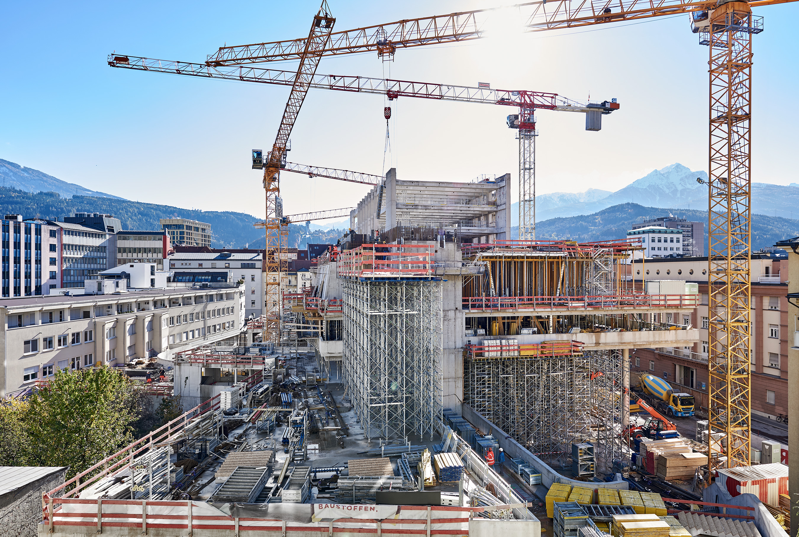 Foto von einer Baustelle eines Hochhaus umzingelt von mehreren Kränen