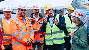 Photo of several people wearing construction helmets and protective jackets