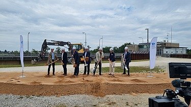 Seven men holding a spade