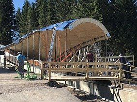 Foto von einer Baustelle im Wald, wo eine Überdachung aus Holz gebaut wird.      