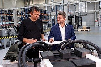 Photo of two people standing behind a workbench on which batteries are placed