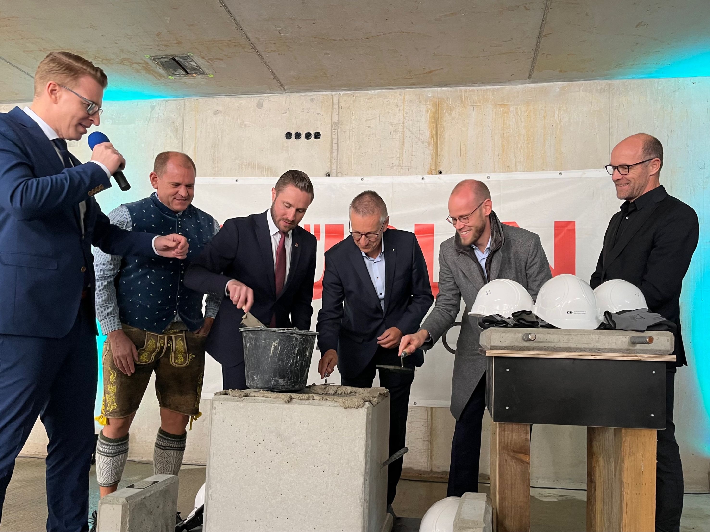 Foto von mehreren Männern im Anzug, die Beton in einen Stein verstreichen. 