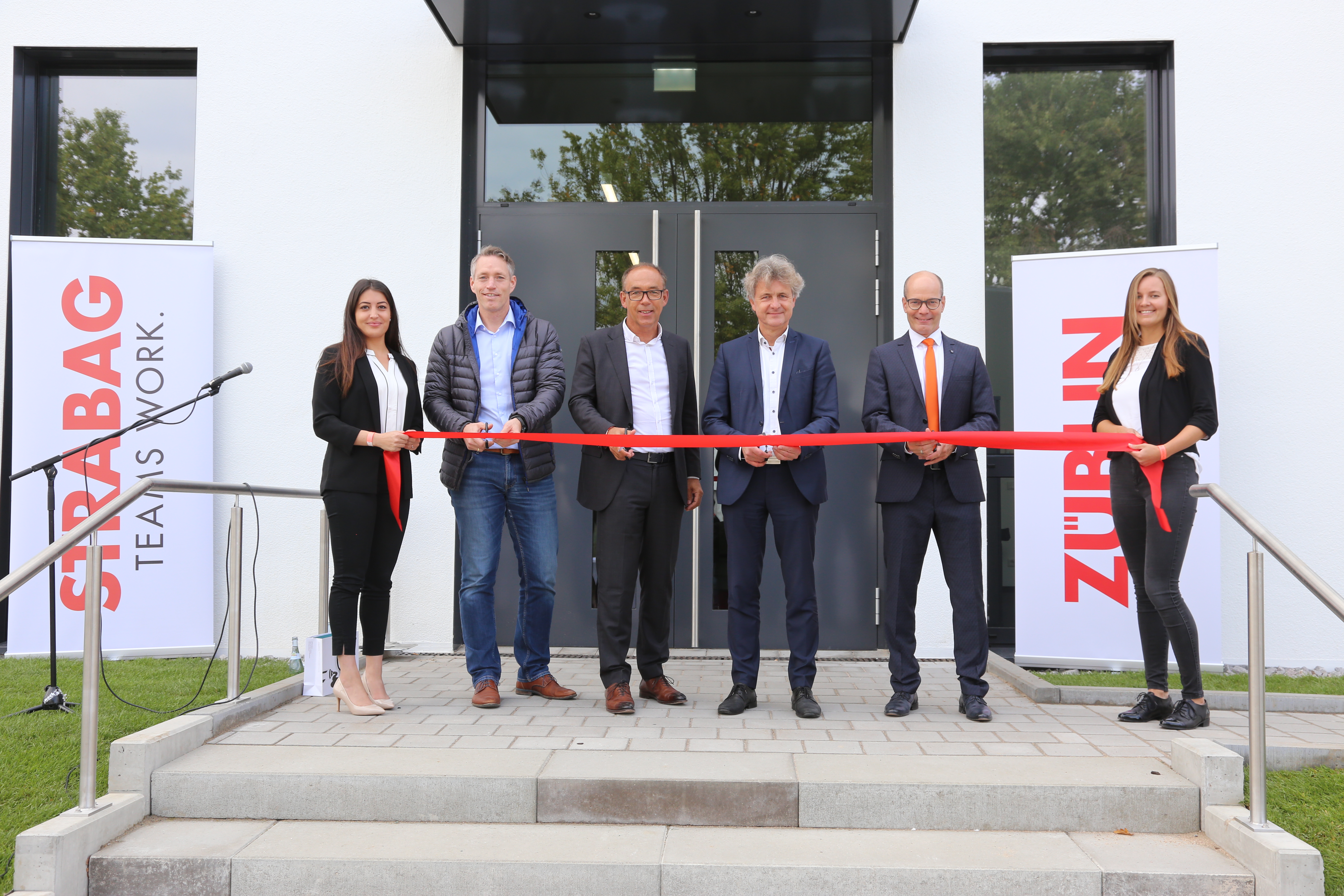 Foto von mehreren Personen bei der Einweihung des neuen Erweiterungsbaus der ZÜBLIN-Direktion in Karlsruhe, die ein rotes Band durchschneiden. 