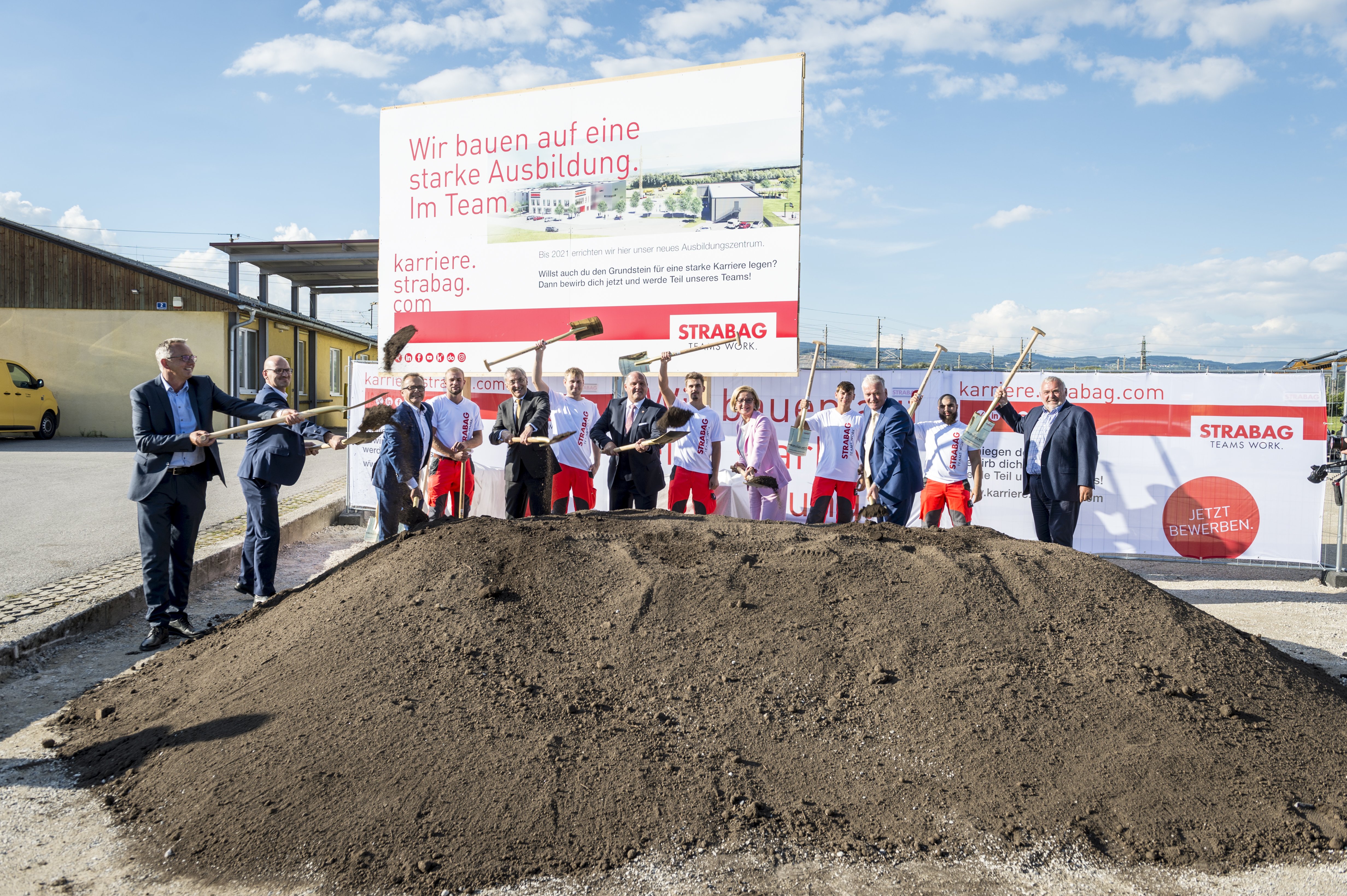 The picture shows several people behind a pile of earth at the symbolic ground-breaking ceremony
