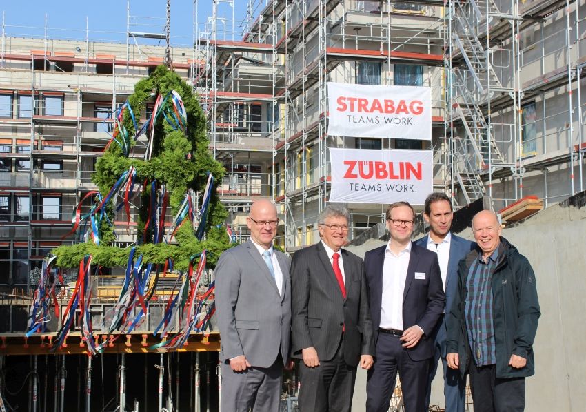 Foto von freundlich schauenden Männern auf einer Baustelle, beim hissen des Richtkranzes.  