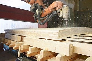 Foto beim bearbeiten von Holz mit einer Industriebohrmaschine.  