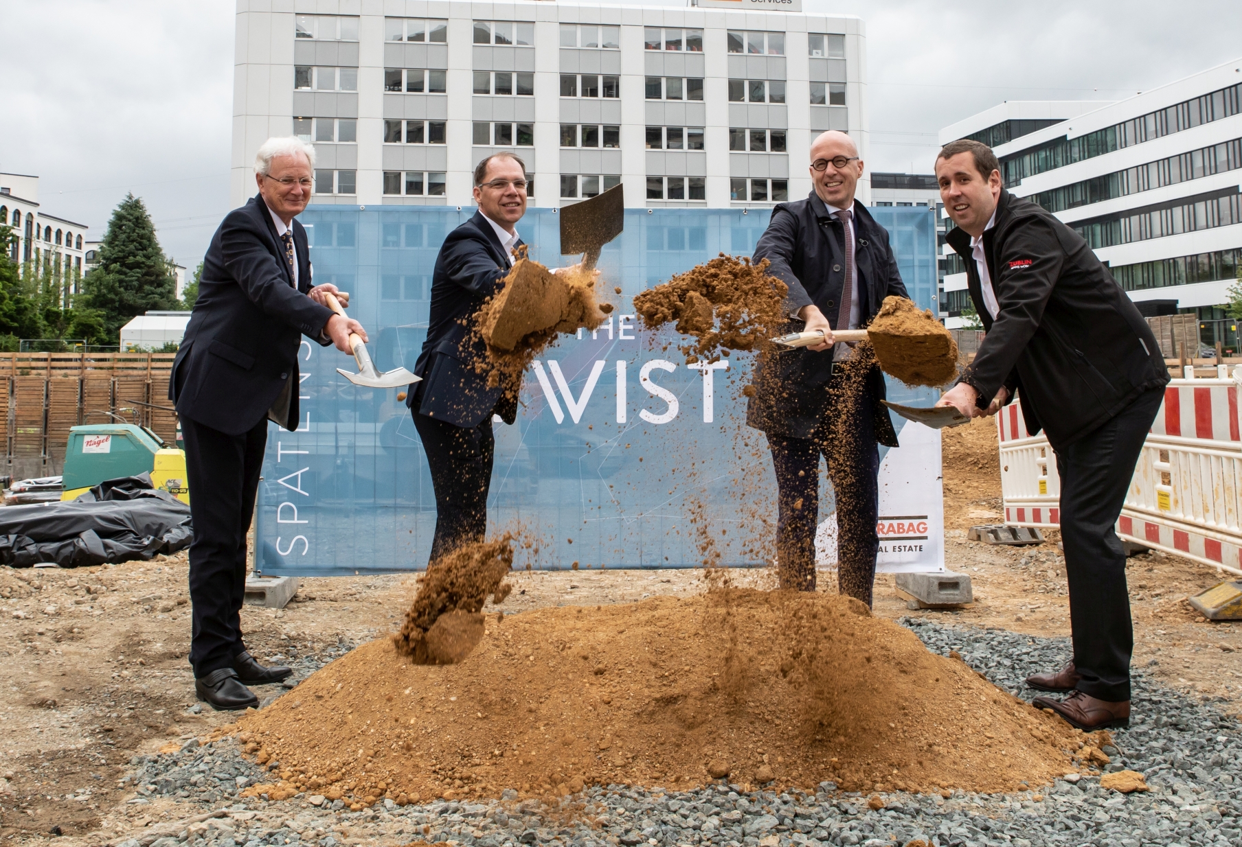 Foto von vier Männern, die mit einem Spatzen, Erde von einem Haufen Erde hochwerfen.  
