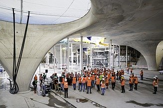 Foto von mehreren Personen in Schutzausrüstung auf einer Baustelle.   