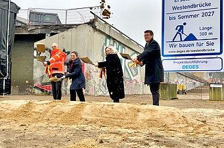 vier Personen schaufeln Sand