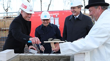Foto von vier Männern bei der Grundsteinlegung für die Erweiterungsbau der Techniker Krankenkasse in Hamburg.