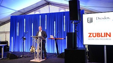 Foto von einer Rede von einem Mann in Anzug. 