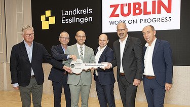 Handover of the keys to the Esslingen District Office The picture 6 people in a row holding a large key