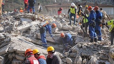 The picture shows relief workers at an earthquake site with rubble