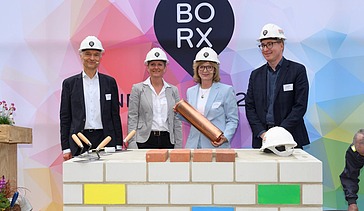Foto von mehreren Personen die schick gekleidet, sind bei der symbolische Grundsteinlegung für Bürogebäude BORX.