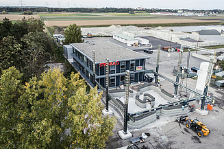 Aerial view of an office building with parking lot, some trees on the right