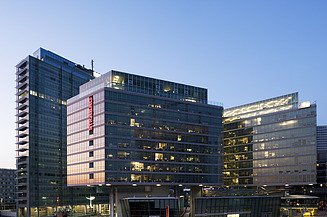 Zu sehen ist das beleuchtete STRABAG Haus bei Abenddämmerung in Wien. 