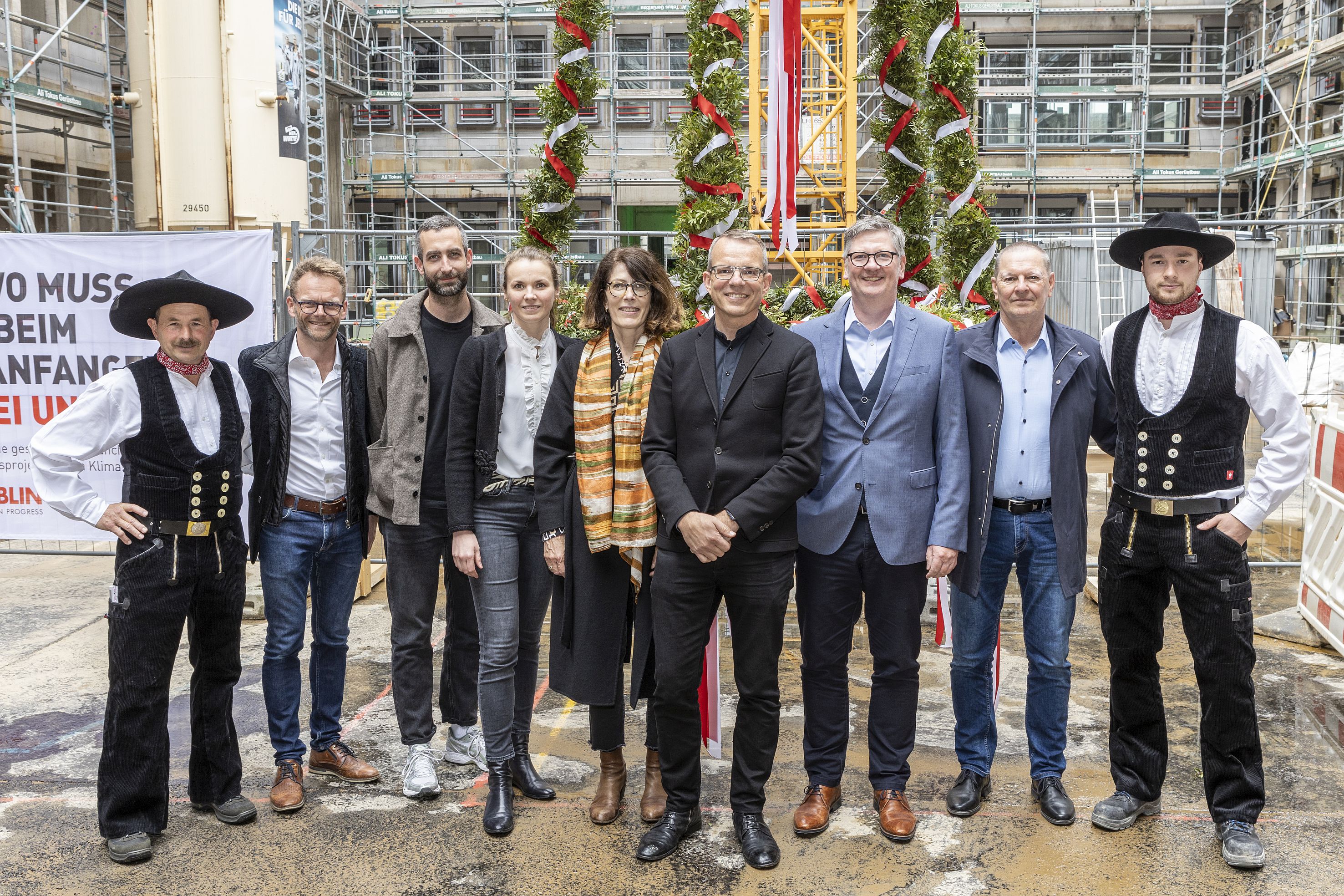 Foto von mehreren schick gekleideten Personen auf einer Baustelle.  