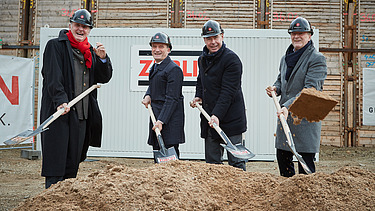 Foto von vier Männern, die auf einer Baustelle, Erde mit einem Sparten schaufeln.