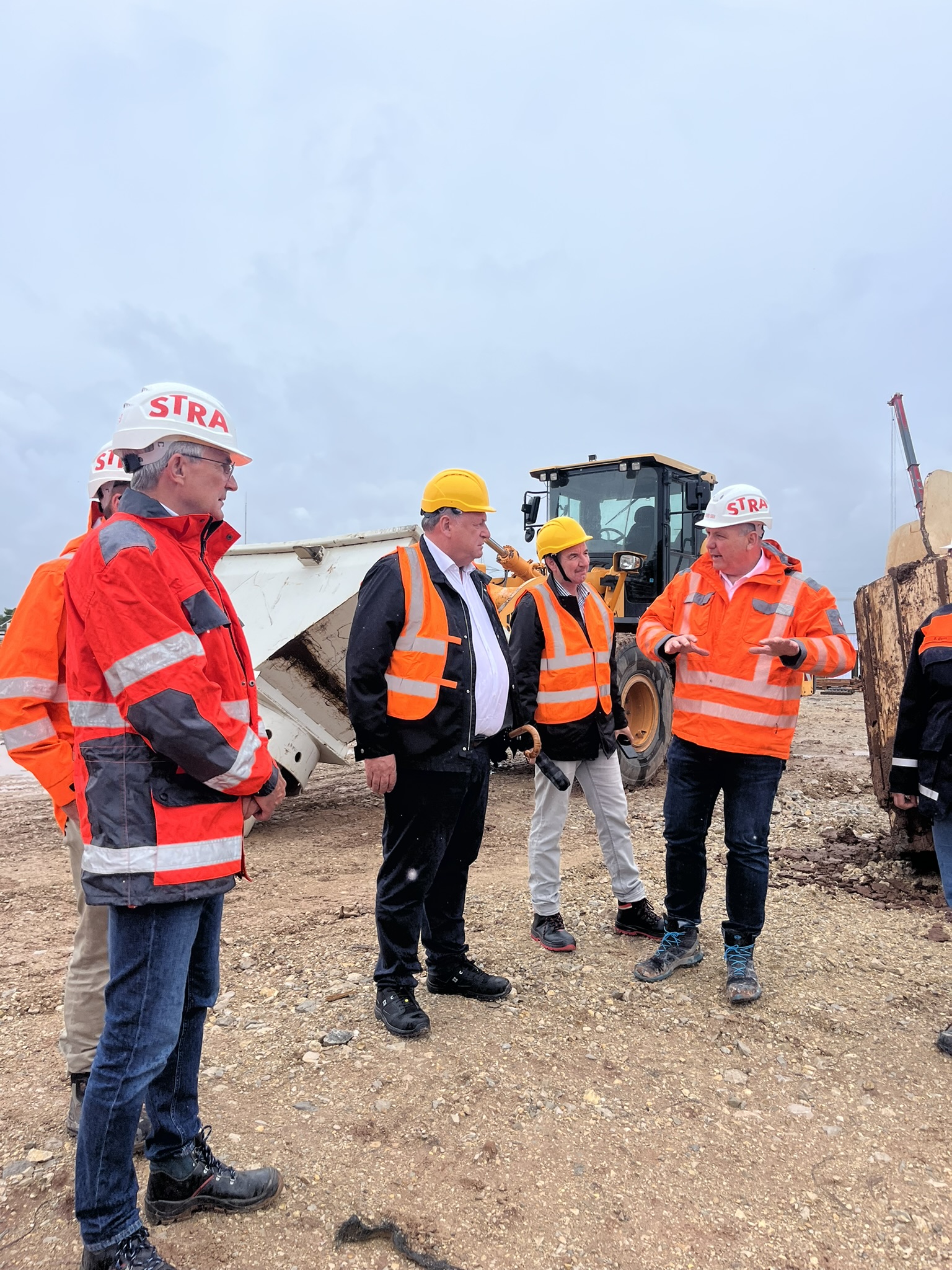 Several people stand in safety clothing on a construction site