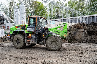 A large wheel loader transports soil in its bucket
