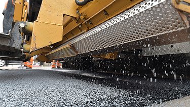 Foto von einer gelben Aspahltstreumaschine