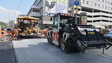 Foto von zwei Straßenbaumaschinen auf einer neuen Straße