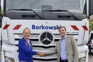 Foto von zwei männlichen Personen, die sich die Hand geben und vor einem LKW stehen mit der Aufschrift Borkowski