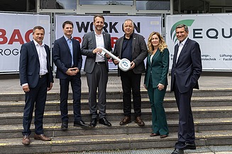 Foto von sechs stehenden Personen bei der symbolischen Baufeldübergabeabe