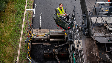 Das Bild zeigt die Praxiserprobung der Robot - Straßenbau 4.0 Maschine auf einer frisch asphaltierten Straße