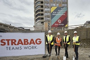 Foto von vier Personen stehen beim Spatenstich vor dem Raiqa Hochhaus, links ist ein STRABAG Transparent