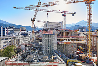 Foto von einer Baustelle eines Hochhaus umzingelt von mehreren Kränen