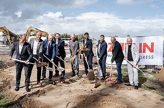 Das Bild zeigt Personen beim Spatenstich mit Schaufeln.