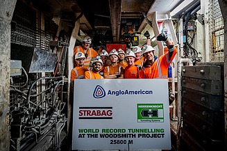 Photo of several people celebrating a tunnel breakthrough and holding a large board in their hands
